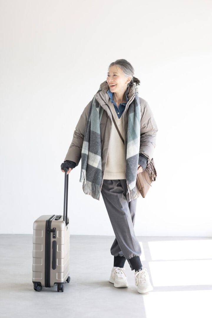 ダウンコート¥17,900，アームウォーマー¥1,500／ともにユニクロ、セーター¥19,990、デニムシャツ¥8,590／ともにザラ（ザラ カスタマーサービス）、パンツ¥47,300／エズミ（リ デザイン）、スニーカー¥35,200／ノーネーム（ストックマン）、バッグ¥20,900／リンク、ストール¥3,990、中にかけたサコッシュ¥1,290、キャリーケース¥19,900／すべて無印良品（無印良品 銀座）