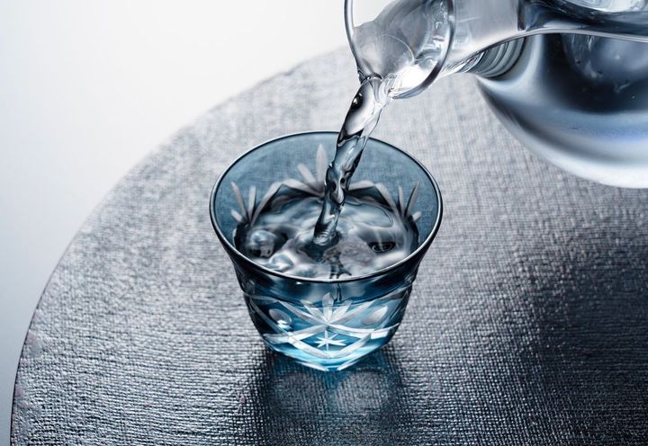 切子の冷酒杯に冷酒を注いでいる手元