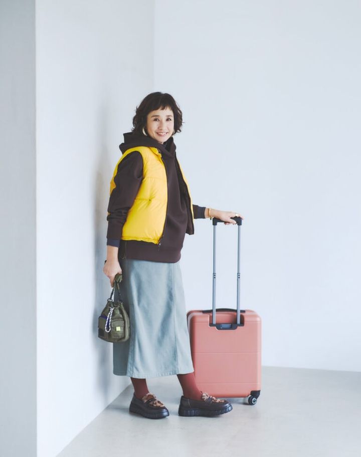 ダウンベスト¥19,800 ／フリーダ（フリークス ストア渋谷）、パーカ¥7,990／アンフィーロ、タートルネックカットソー¥3,850／エルーラ（アダストリア カスタマーサービス）、スカート¥16,500／マーモット（サードシップ）、ピアス ¥51,300／アビステ、バングル¥28,600、リング¥14,300／ともにワンエーアールバイウノ アエレ（ウノアエレ ジャパン）、スーツケース¥81,400／プロテカ（エース）、バッグ¥16,500／アンスリード（アンス リード青山店）、タイツ¥1,210／靴下屋（タビオ）、ローファー¥13,200／アルテミス by ダイアナ（アルテミス by ダイアナ アーバンドック ららぽーと豊洲店）