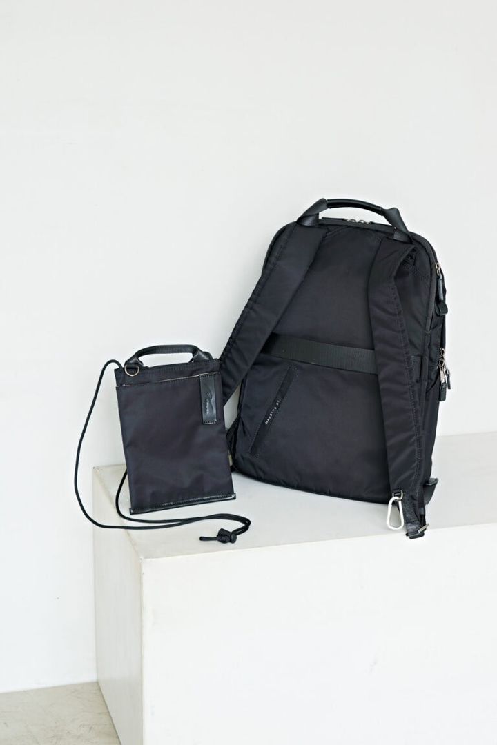 背面には、スーツケースの伸縮ハンドルにセットできるベルトつき。スマホが入るサコッシュもついています。