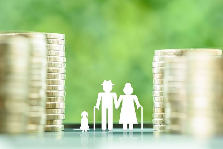 積み上げたコインの間に立つ高齢夫婦の人形