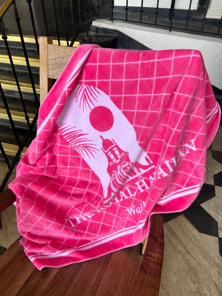 ホテルのイラストがお洒落なホットピンクのビーチタオル（$88）。