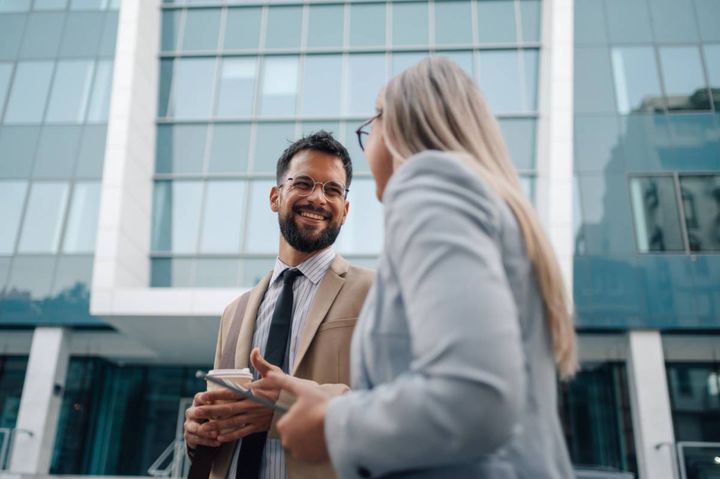屋外を歩きながら同僚の女性と話す男性