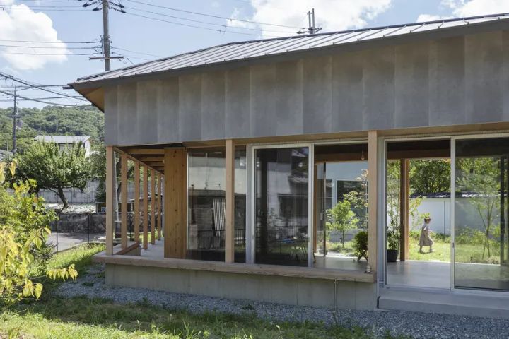木材とコンクリートで作られたモダンな日本の家。 屋根が低く、窓が大きく、屋外とのつながりが感じられる。