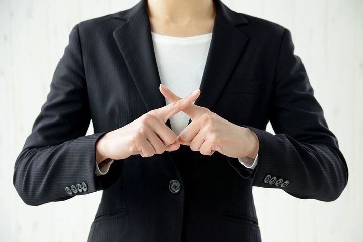 手でバツを作る女性