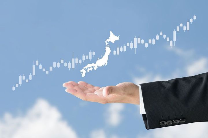 ビジネスマンの手の上にある日本地図と、上昇する株価チャート