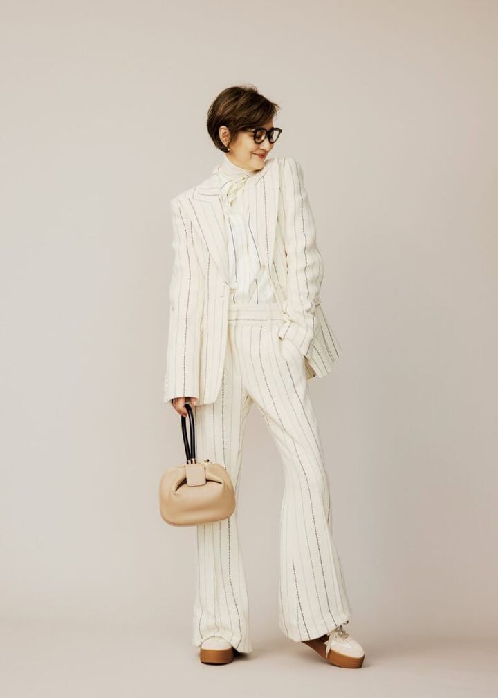 ジャケット¥623,700、中に着たタートルニット¥172,700、ブラウス¥289,300、パンツ¥334,400、バッグ¥506,000／すべて ガブリエラ ハースト（ガブリエラ ハースト ジャパン）、メガネ¥58,300／ユウイチ トヤマ（コンティニュエ）、ピアス¥53,400、リング〈右〉¥70,000／ともに トムウッド（トムウッド 青山店）、シューズ¥75,900／ホーガン（トッズ・ジャパン）