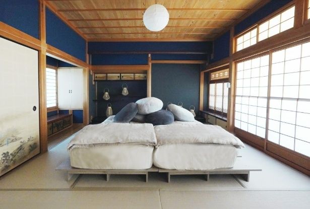 深い藍色の壁と木の天井が醸す静けさの中に、柔らかな寝具がそろった和室空間が広がる