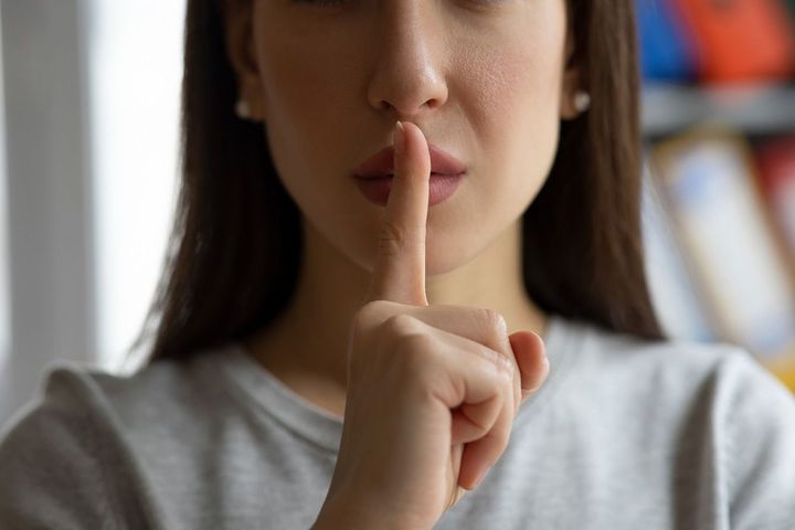 唇の前で人差し指を立てて静かにするようジェスチャーをする人