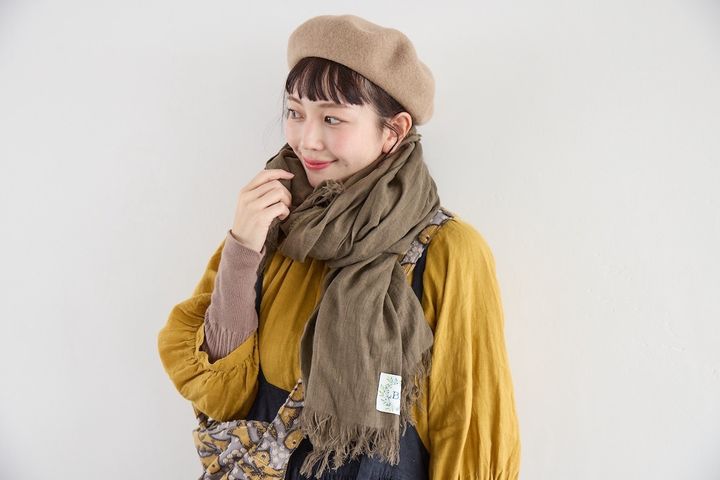 カーキ色のショールとベージュのベレー帽を重ねたナチュラルな顔まわりのスタイリング