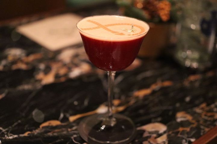 表面にゴールドのセルペンティ（蛇）が描かれたシグニチャーカクテル「セルペンティ」。日本のウイスキーをベースにストロベリー、サフランなどをブレンド。