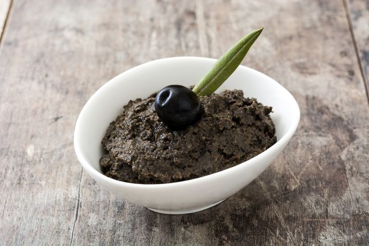 Black olive tapenade with anchovies, garlic and olive oil on wooden background アンチョビペースト