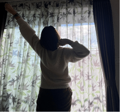 窓際で伸びする女性