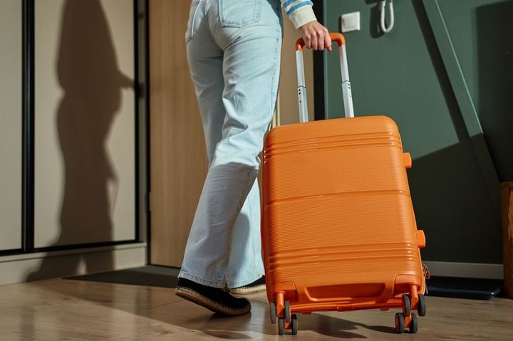 スーツケースを手に、ドアから出ていこうとしている女性