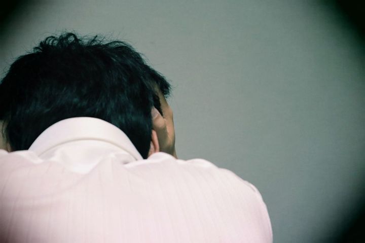 うずくまって頭を抱えている男性