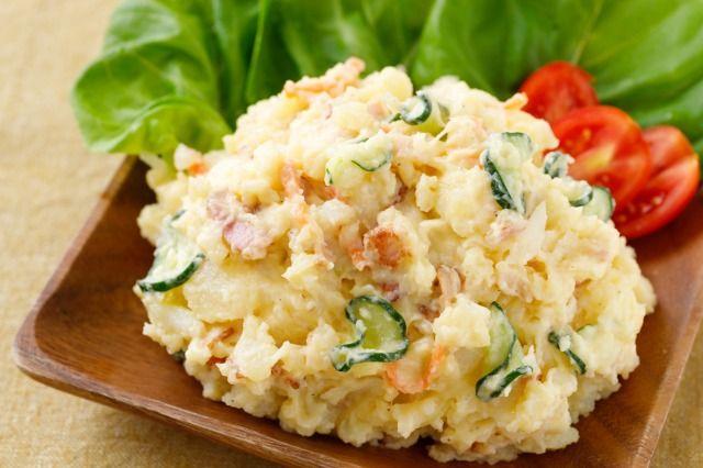 木製の器に入ったポテトサラダとトマトとレタスの画像 木製机