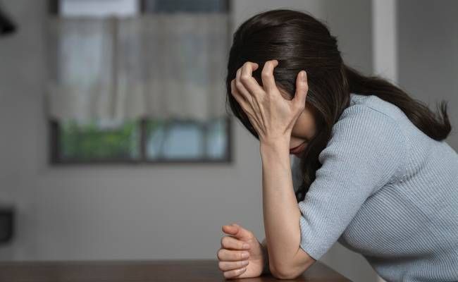 頭を抑えて痛みに耐える女性のイメージ