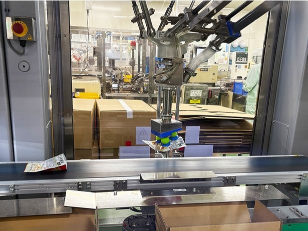 青と緑の吸盤のようなもので流れてくるパウチをキャッチ、手前の段ボール箱に入れていく