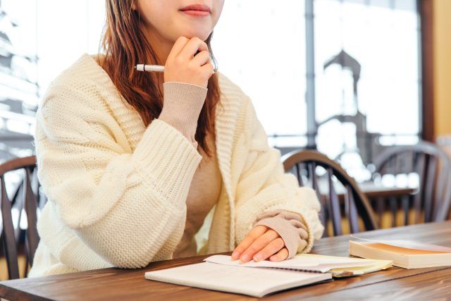 ノートを開いて考え事をする女性