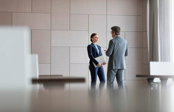 会議室で立って話し合う男女