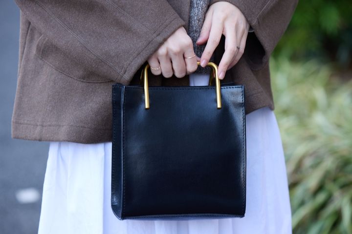 ナチュラルコーデに合わせた、黒×ゴールドのスクエアフォルムのバッグ