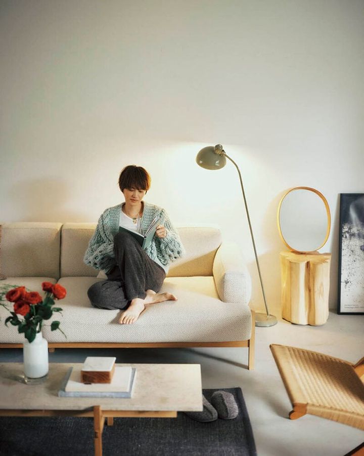 フロアランプ【6556-F】15万5980円（カイザー・イデル）、手縫いされたレザーフレームにレトロなオーバル型ミラーをセット。オーバルミラー3万6300円（モヘイム）、テーブルの上のフラワーベース1万7600円（ジュー／すべてアクタス）ニットカーディガン11万円（ミスターミトンズ／RHC ロンハーマン） パンツ2万8600円、スリッパ1万4300円（ともにベアフット ドリームズ／リトルリーグ インク） タンクトップ5940円（サク・レ／ロイネ） ネックレス10万5600円（グレイン モートン／ロンハーマン）