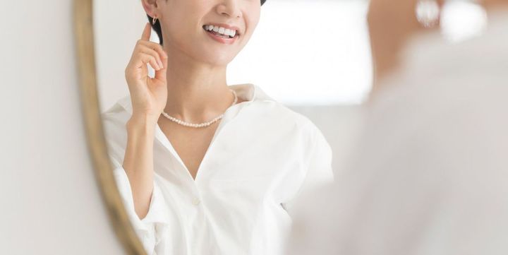 鏡でイヤリングを確認している女性