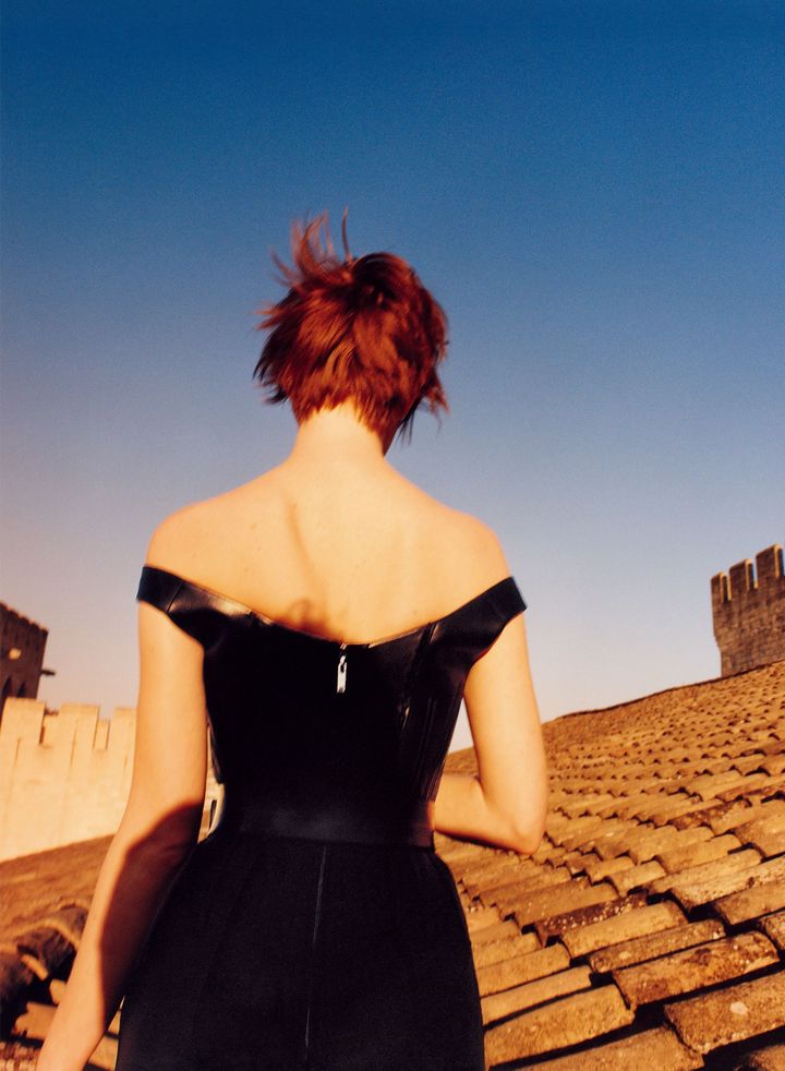 根底に宿る秘めた想い 彼女のアイコニックな赤毛が映える、美しいショルダーラインが際立つバックコンシャスなボディスーツ。ベルトが一層くびれたラインを強調して。エマは芯の強い華々しい印象とは裏腹に、根底には常に不安を抱え、その感情は“いつ、どんなときにも” 離れないのだと話す。<br /> ボディスーツ ベルト ともに参考商品／ともにLOUIS VUITTON（ルイ・ヴィトン クライアントサービス）