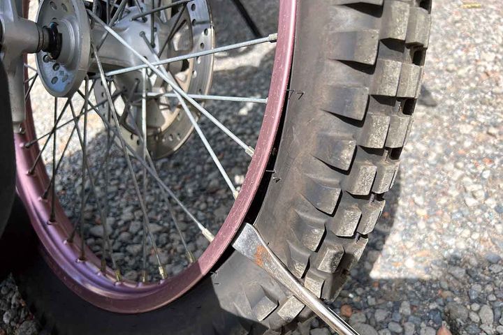 を使って両面のビードを落とす。ヘビーチューブだと落ちにくく苦戦するかもしれないが、ノーマルチューブ＋トライアルタイヤならばタイヤレバーを使わず、手だけで落とせた