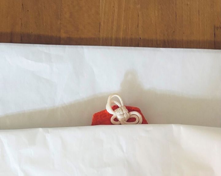 白い紙にくるまれたお守り お守りや御札を家で処分する方法