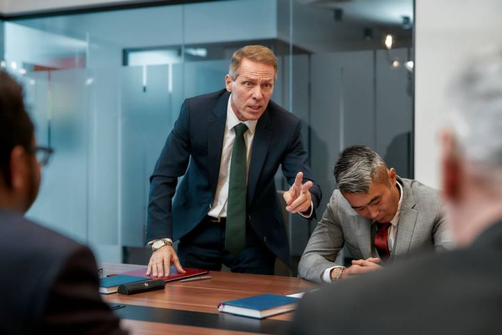 会議中に立ち上がって発言する男性