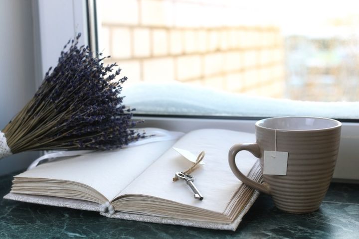 ビンテージノートや本、マグカップ、ラベンダーのドライフラワー 窓の外の雪