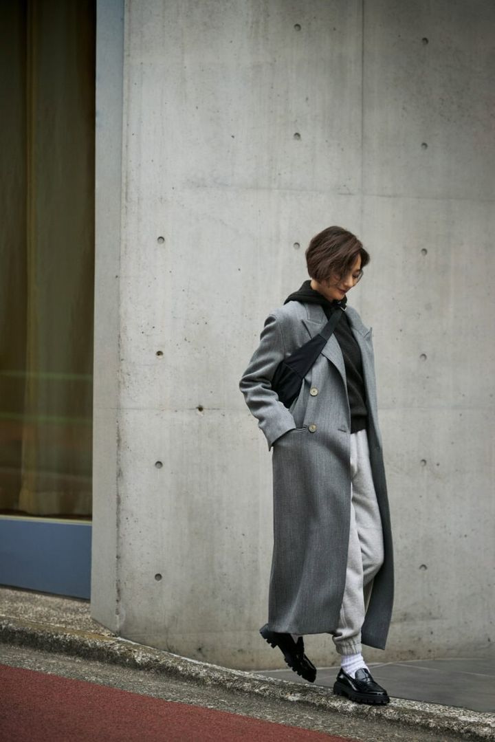 コート：テラ、ニット：ル メール、スエットパンツ：ブラミンク、バッグ：ジル・サンダー、ソックス：ショウワタベ、靴：トッズ