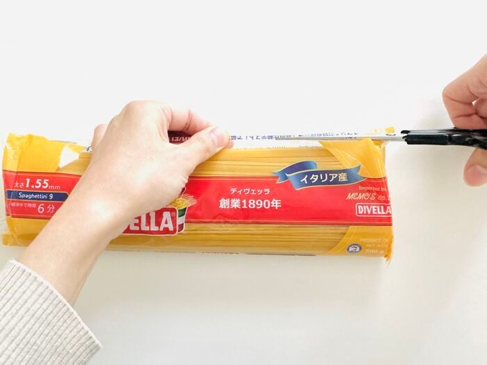 パスタ袋の上部をハサミで切っている