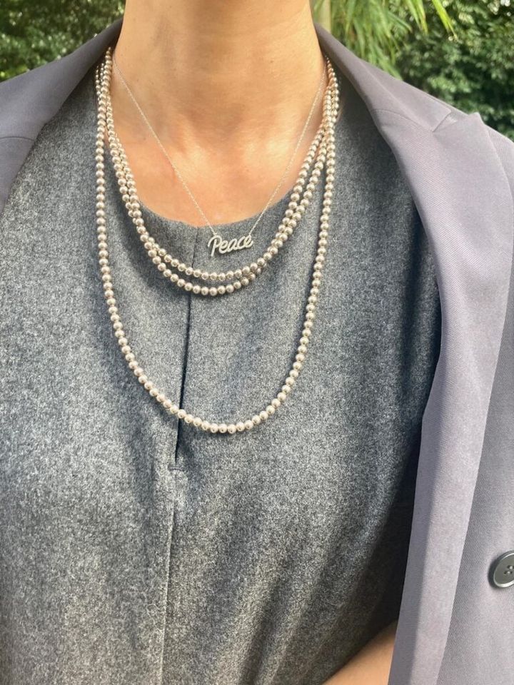 シルバーカラーのレターペンダントと、クラシックな３連パールを重ね付け。