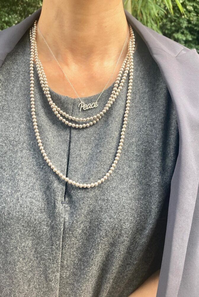 シルバーカラーのレターペンダントと、クラシックな３連パールを重ね付け。