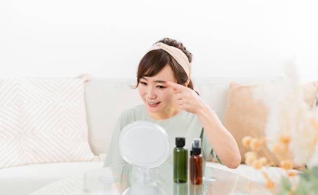 眉を指して笑顔になっている女性のイメージ