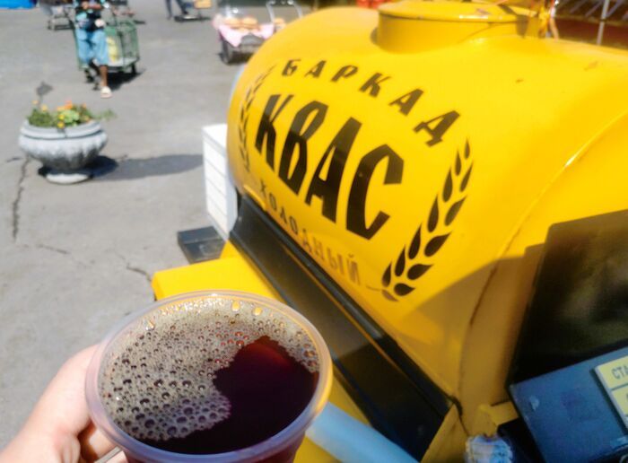 東欧や中央アジアで親しまれている微炭酸の微アルコール飲料クワスを、屋外の売り場でカップに注いだ様子