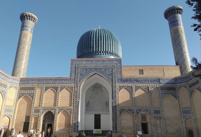 ウズベキスタン・サマルカンドの青いタイル装飾が美しい歴史建築。青空の下に立つドームとミナレット