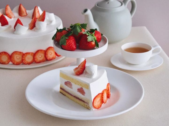 いちごが添えられたケーキと紅茶の入ったカップの静物写真。