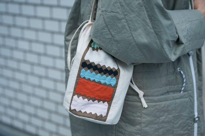 赤をポイントで効かせた、パッチワークデザインの小ぶりな巾着型バッグ