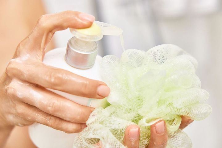 ボトルから液体石鹸をスポンジに注ぐ女性の手