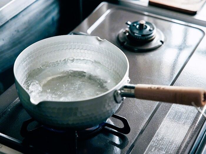 ガスコンロで雪平鍋を使いお湯を沸かしている様子。白湯作りや料理に便利な軽量アルミ鍋は、注ぎ口付きで洗いやすく一人暮らしやミニキッチンにも最適。