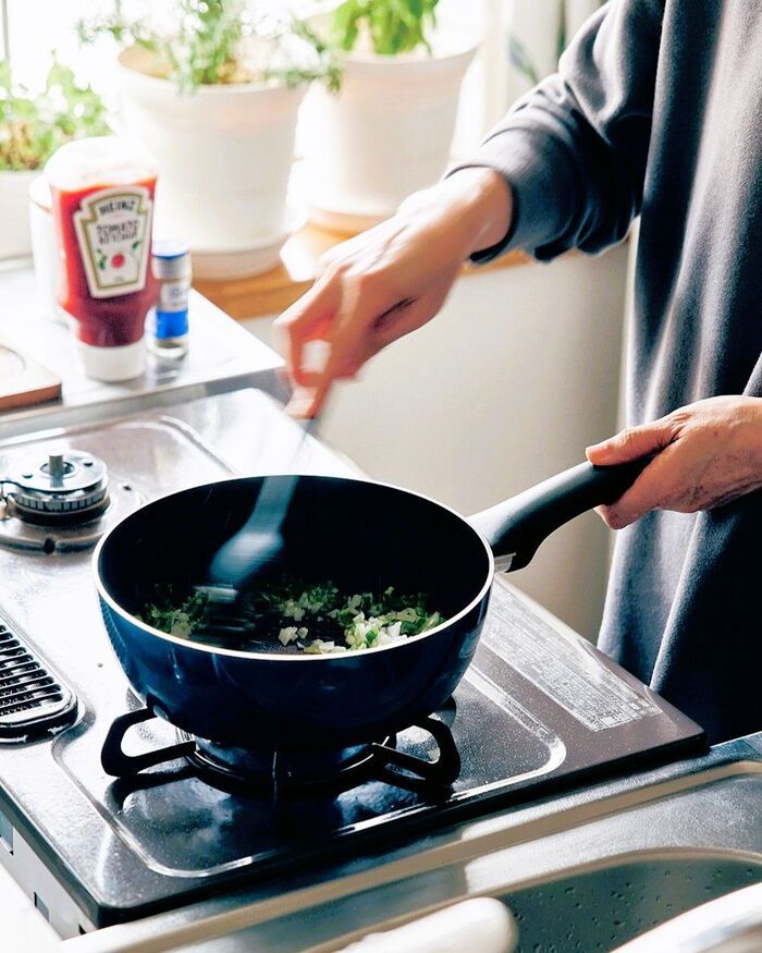 キッチンで深型フライパンを使い、野菜を炒める調理中の様子。コンパクトなガスコンロとちょうどいいサイズのフライパンは、炒め物・煮物・麺ゆでも対応。料理好きに嬉しい使い勝手の良い万能調理器具。