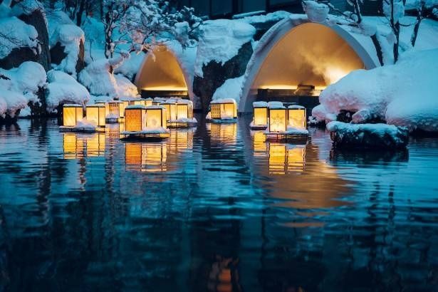 界 津軽の「こぎんかまくら」。雪に覆われた庭に浮かぶ灯籠と、かまくらの柔らかな明かりが水面に映り込む