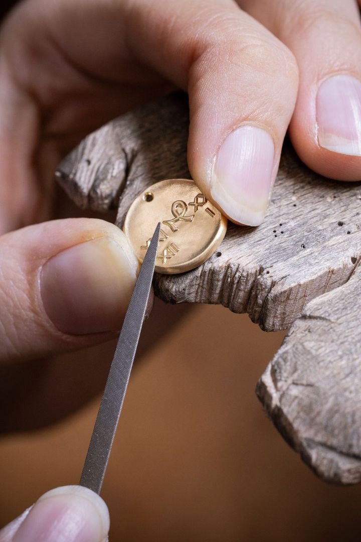 メダルの縁にやすりをかけて美しく仕上げている