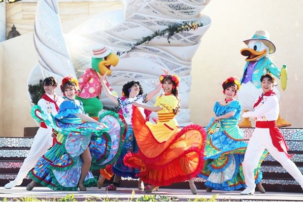 カラフルな衣装を身にまとったダンサーに囲まれ、元気いっぱいに踊るミラベル