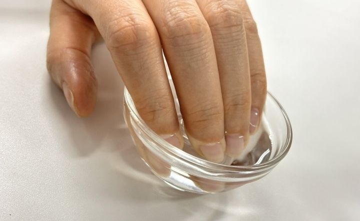 ネイルケアを始めるために、ぬるま湯に指先を浸けて甘皮をふやかしている様子