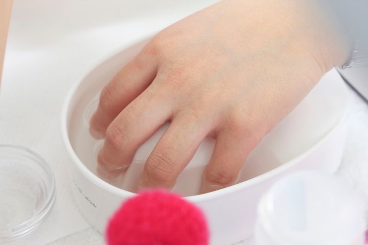 ネイルケアを始めるために、ぬるま湯に指先を浸けて甘皮をふやかしている様子