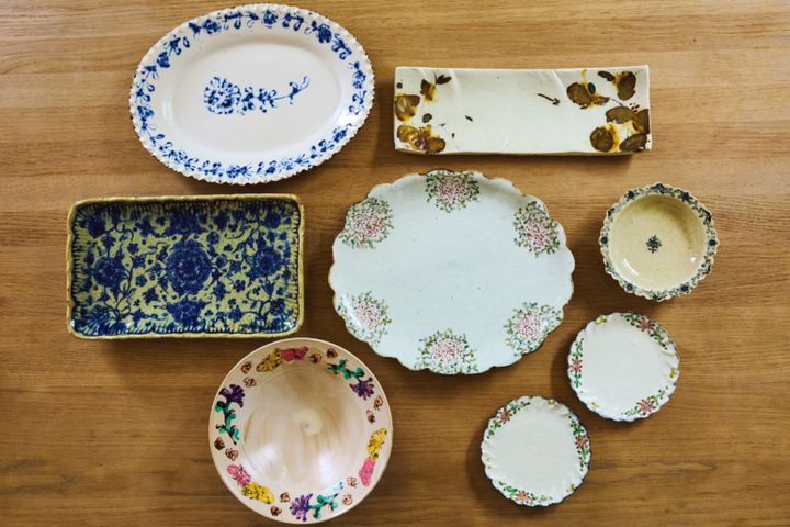 左上から時計まわりに、白地にブルーの花が映える伊藤聡信（あきのぶ）さんの印判皿。シックな長皿とリムに花をあしらった丸皿3枚は「天平窯」のもの。「岡晋吾さん、さつきさんご夫婦による窯で、長皿は晋吾さん、丸皿はさつきさんの作品です。もともと母が好きで私も20年以上前から集めています。やさしい筆運びが素敵でしょう？」。蝶々柄の鉢はヨシノヒトシさん、ブルーの花が咲き誇る長皿はイムサエムさんのもの。「イムサエムさんの器は少々重いものの、料理映えがすごい！昨年引退され、もう新作が見られないと思うと寂しいですね」。中央の楕円皿も「天平窯」のもの。